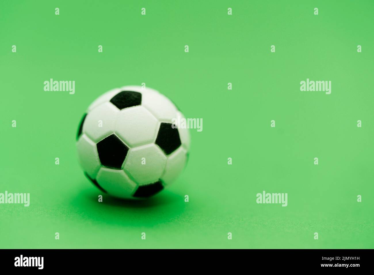 pelota de fútbol en miniatura sobre fondo verde Foto de stock