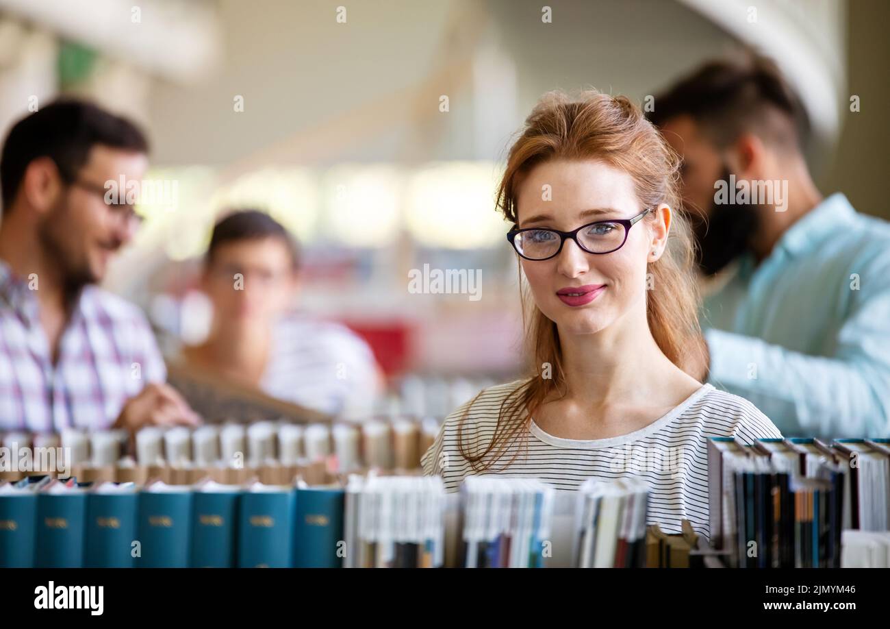 Feliz grupo de estudiantes que estudian y trabajan juntos en una biblioteca universitaria Foto de stock