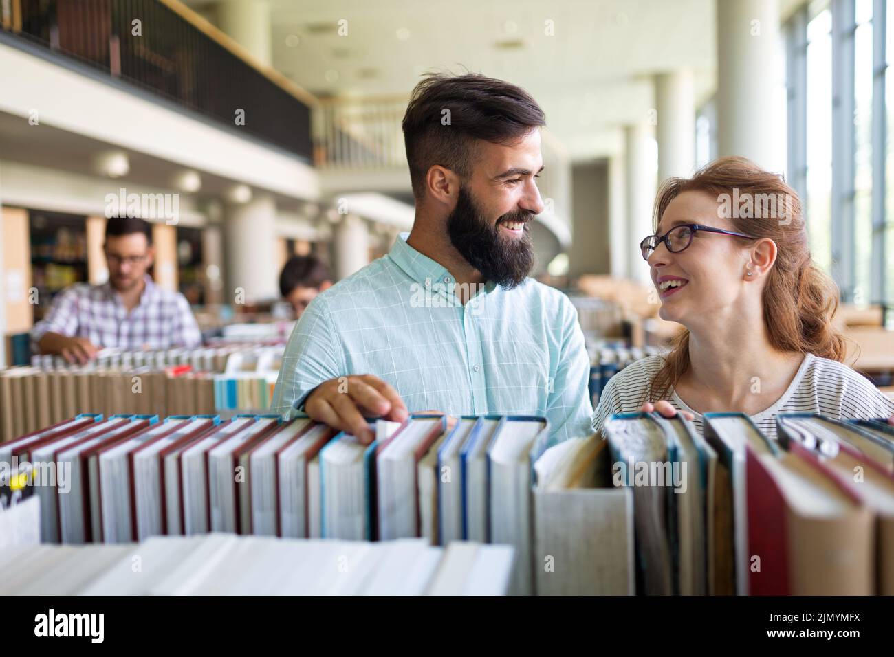 Felices estudiantes universitarios estudiando con libros en la biblioteca. Grupo de personas multirraciales en la universidad Foto de stock