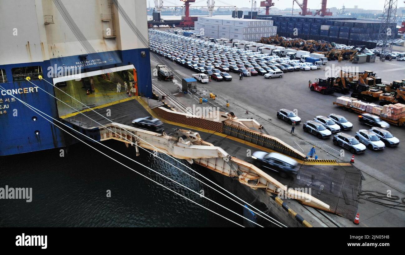 Qingdao. 7th de Ago de 2022. La foto aérea tomada el 7 de agosto de 2022 muestra vehículos comerciales que son embarcados en un buque de carga de ro-ro para salir hacia África en el puerto de Qingdao en Qingdao, en la provincia de Shandong en el este de China. Con mucho este año, el volumen de exportación de vehículos comerciales del puerto de Qingdao ha crecido más del 90 por ciento año con año. Crédito: Li Ziheng/Xinhua/Alamy Live News Foto de stock