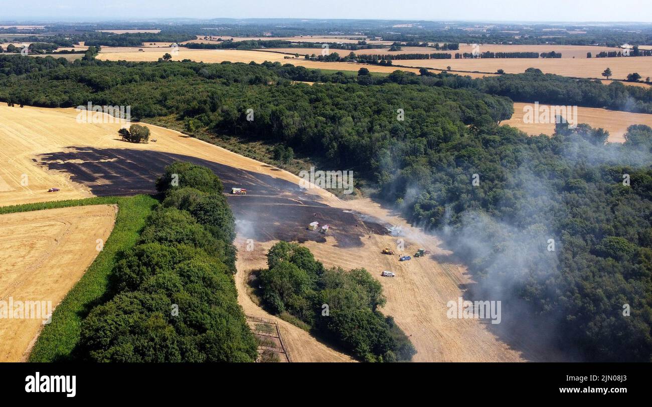 Los bomberos controlan un incendio de campo cerca de Ashford en Kent. Gran Bretaña está preparada para otra ola de calor que durará más que el período de calor récord de julio, con máximos de hasta 35C que se esperan la próxima semana. Fecha de la foto: Lunes 8 de agosto de 2022. Foto de stock