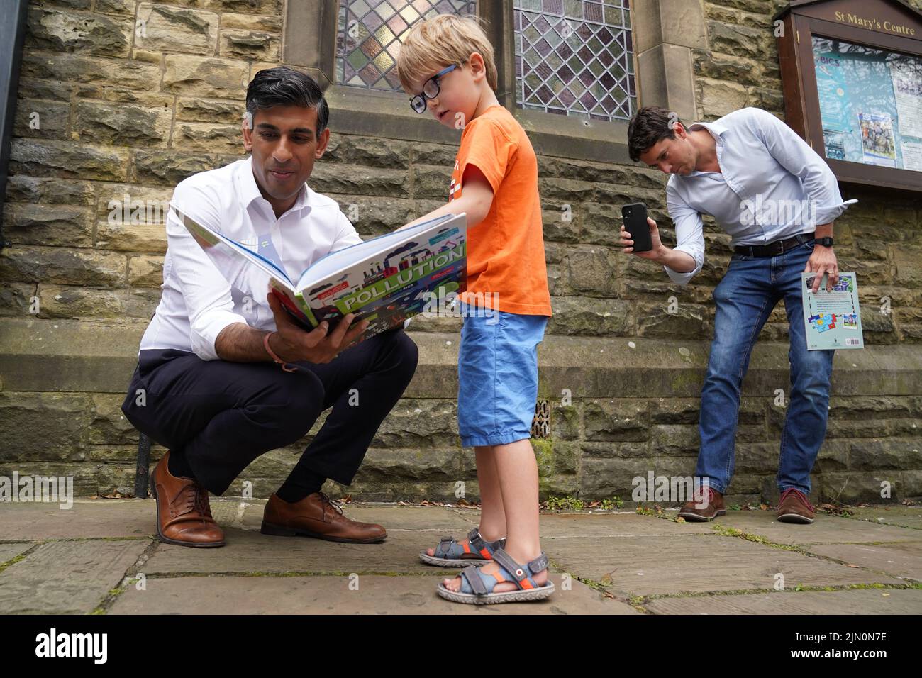 Rishi Sunak (izquierda) mira un libro con Teddy Openshaw, de cuatro años, de Whitewell, mientras su padre Henry toma una fotografía, después de un evento en Ribble Valley, realizado como parte de su campaña para ser líder del Partido Conservador y próximo primer ministro. Fecha de la foto: Lunes 8 de agosto de 2022. Foto de stock