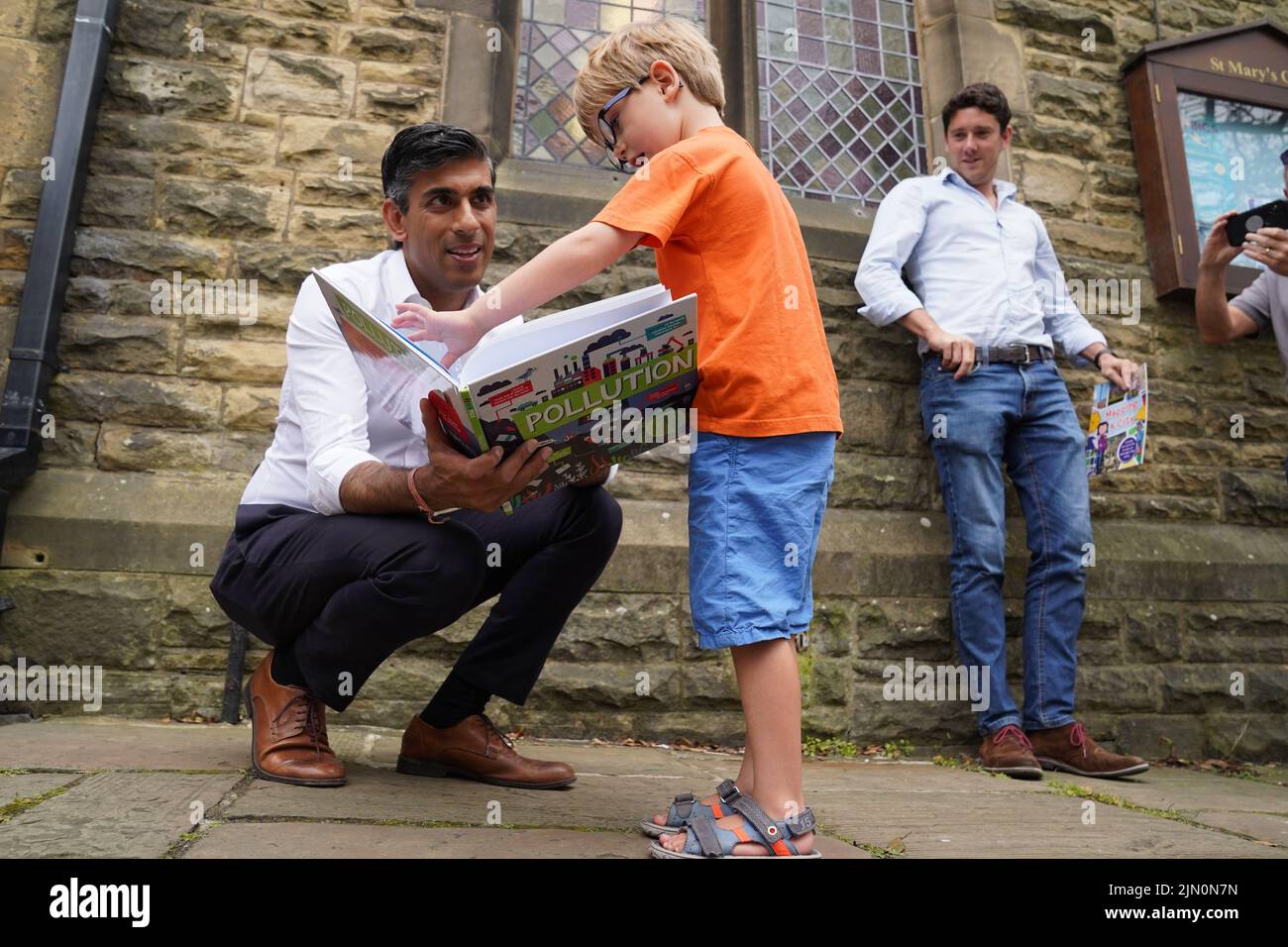 Rishi Sunak (izquierda) mira un libro con Teddy Openshaw, de cuatro años, de Whitewell, como su padre Henry (derecha) observa, después de un evento en Ribble Valley, celebrado como parte de su campaña para ser líder del Partido Conservador y próximo primer ministro. Fecha de la foto: Lunes 8 de agosto de 2022. Foto de stock