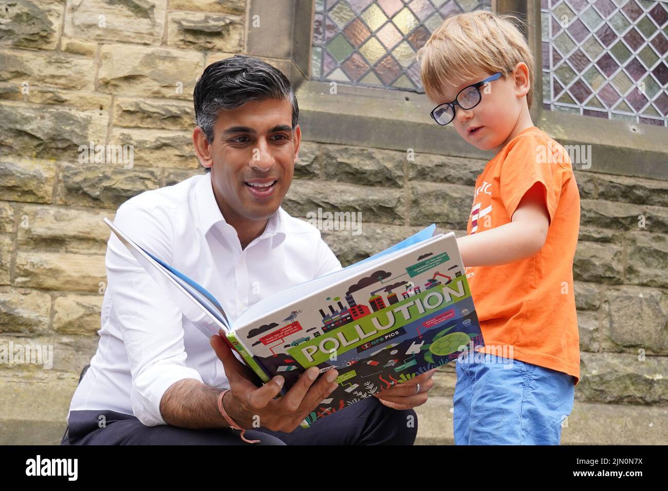 Rishi Sunak (izquierda) mira un libro con Teddy Openshaw, de cuatro años, de Whitewell, después de un evento en Ribble Valley, realizado como parte de su campaña para ser líder del Partido Conservador y próximo primer ministro. Fecha de la foto: Lunes 8 de agosto de 2022. Foto de stock