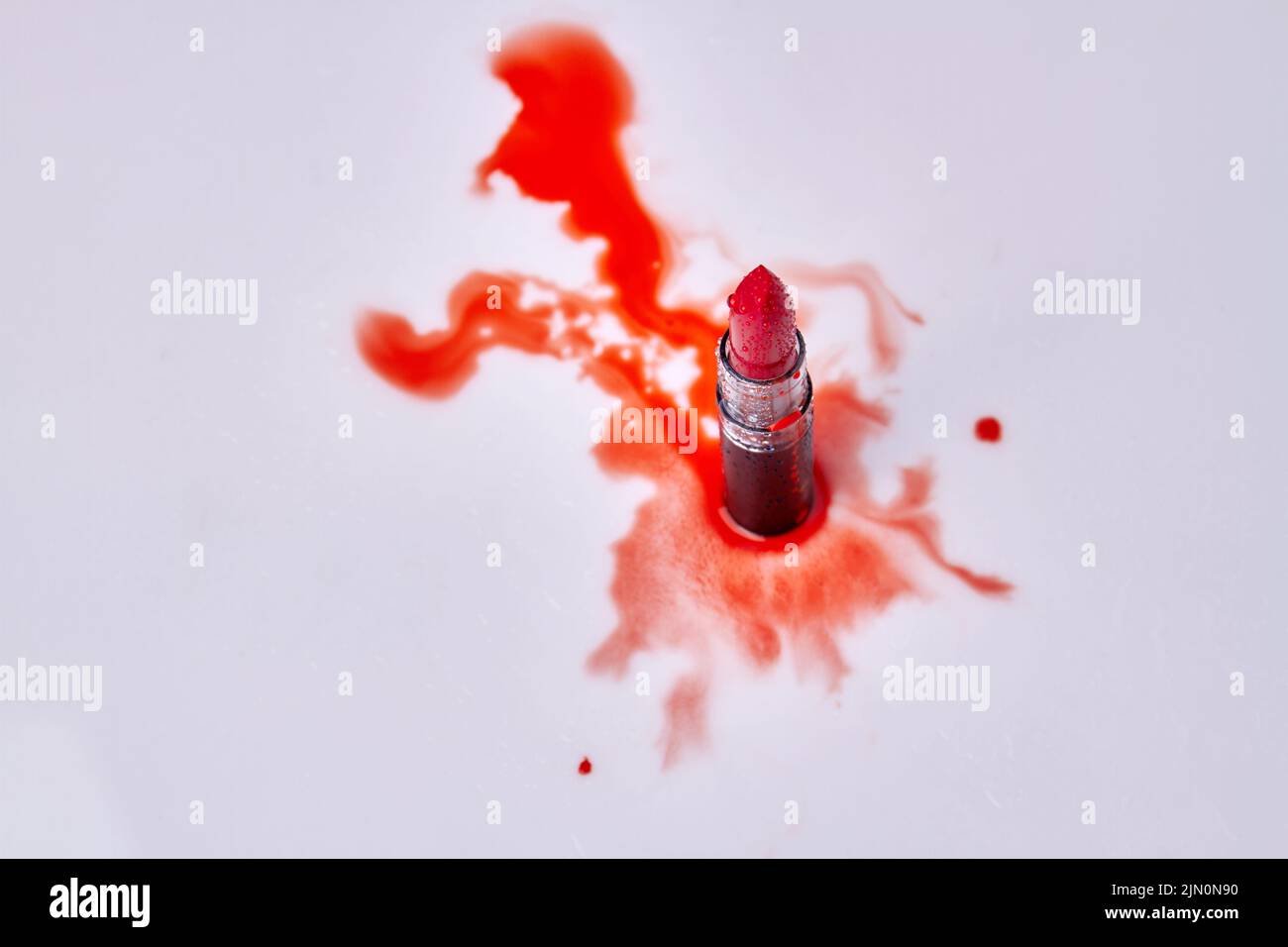 Vista superior del lápiz labial rojo con gotas de agua. Manchas rojas sobre fondo blanco. Foto de stock