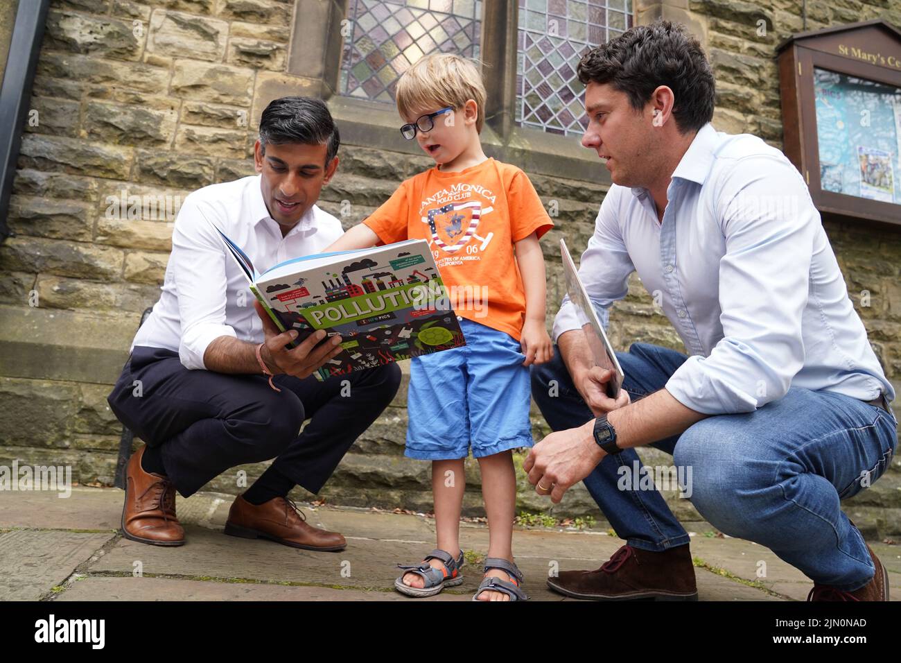Rishi Sunak (izquierda) mira un libro con Teddy Openshaw, de cuatro años, de Whitewell, con su padre Henry, tras un evento en Ribble Valley, celebrado como parte de su campaña para ser líder del Partido Conservador y próximo primer ministro. Fecha de la foto: Lunes 8 de agosto de 2022. Foto de stock