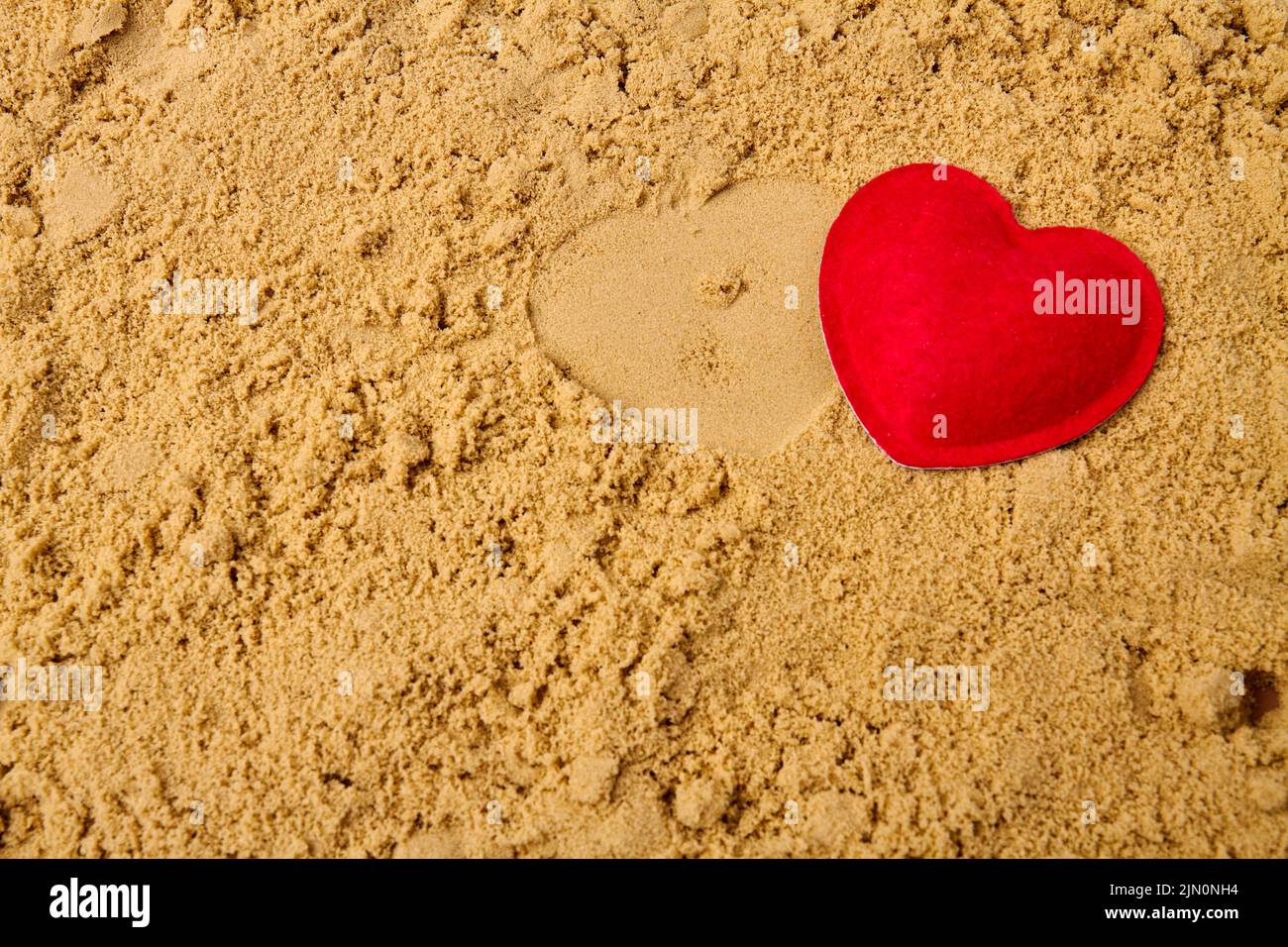 Corazón rojo en la arena de la playa de verano. Amor y día de San Valentín concepto. Foto de stock