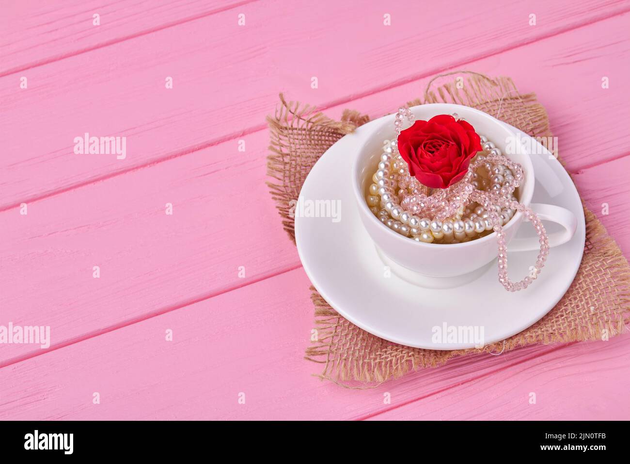 Taza de café blanca con joyas de perlas y flores rojas. Día de San Valentín concepto. Foto de stock