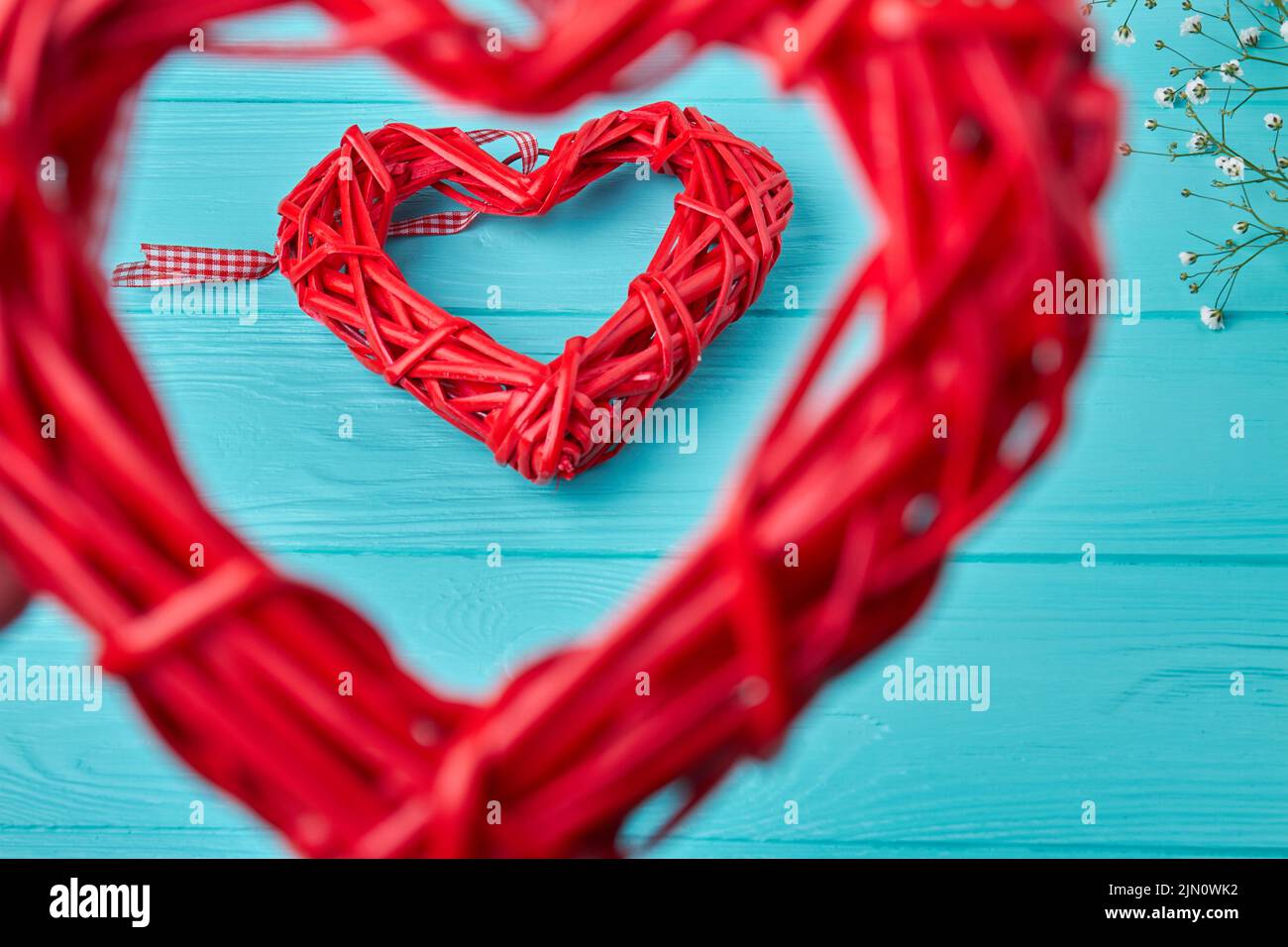 Primeros planos rojo wickers corazón marcos en azul escritorio de madera. Día de San Valentín concepto. Foto de stock