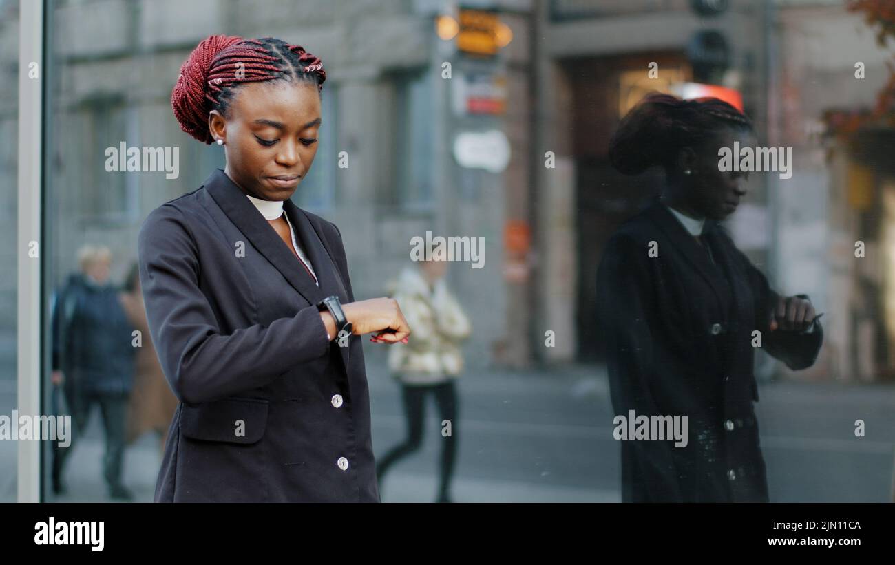 Joven mujer de negocios afro americana chica que camina cerca del edificio de la oficina de la empresa llegar tarde para la entrevista reunión se mueve en la calle en la ciudad Foto de stock