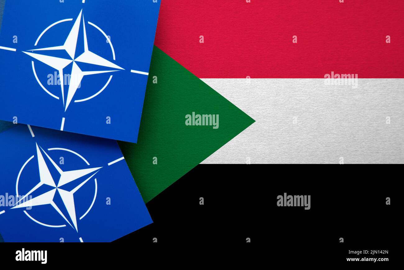 LONDRES, Reino Unido - Agosto de 2022: Logotipo de alianza militar de la Organización del Tratado del Atlántico Norte (OTAN) en una bandera de Sudán Foto de stock