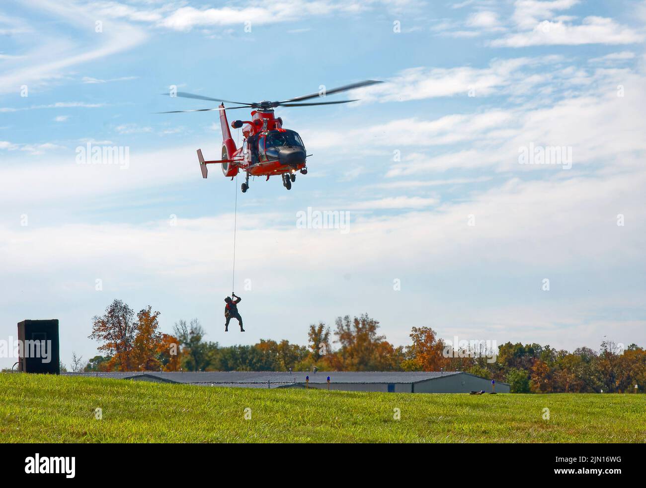 Vuelo en helicóptero, guardacostas de EE.UU., campo de hierba, avión de ala giratoria, transporte, Palas rotando, movimiento, hombre sobre cable descendente, helicóptero M Foto de stock