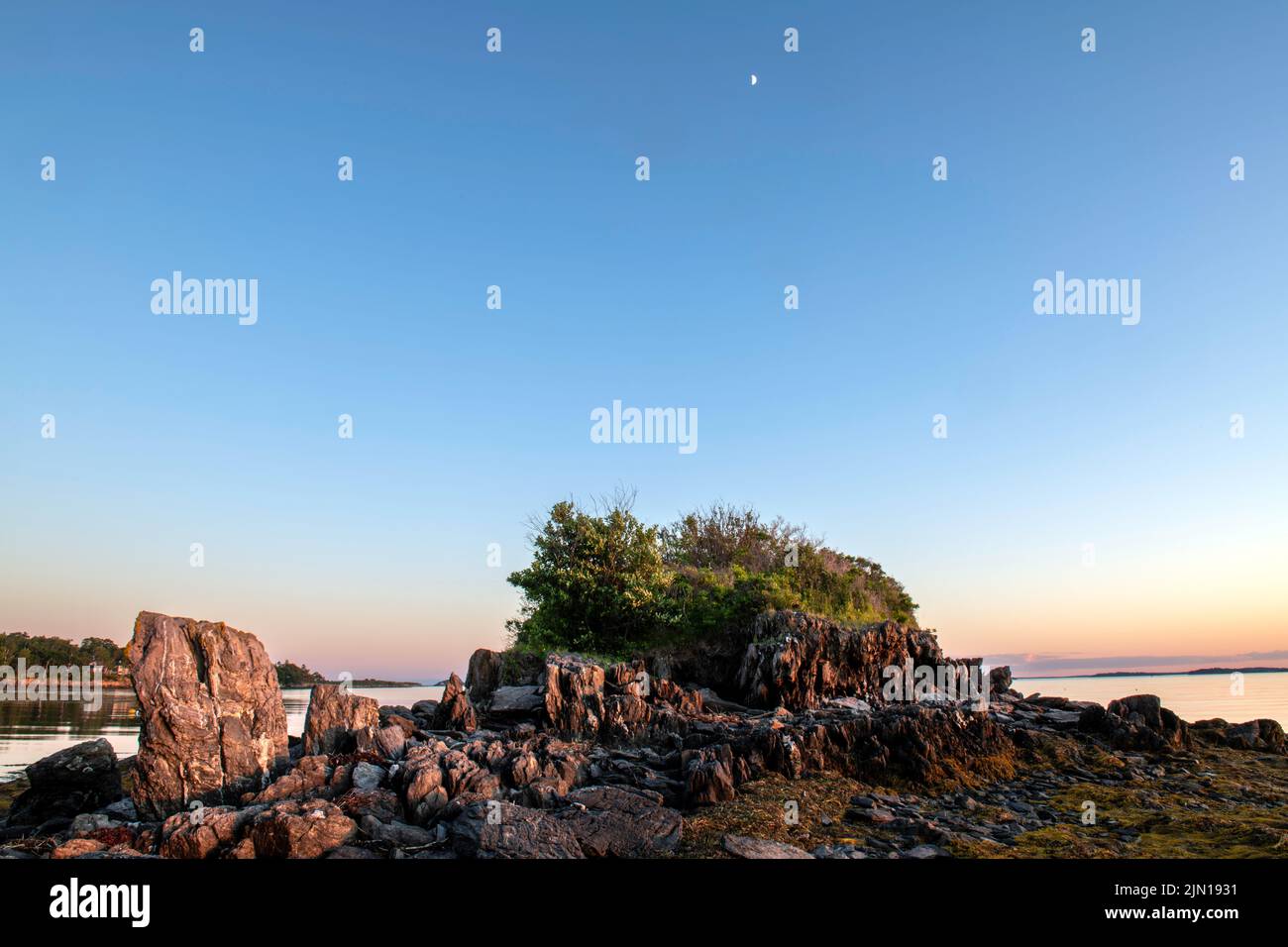6 de julio de 2022. 8:14 pm. Isla Barnes. Casco Bay, Maine. La luna se levanta antes de la puesta del sol Foto de stock