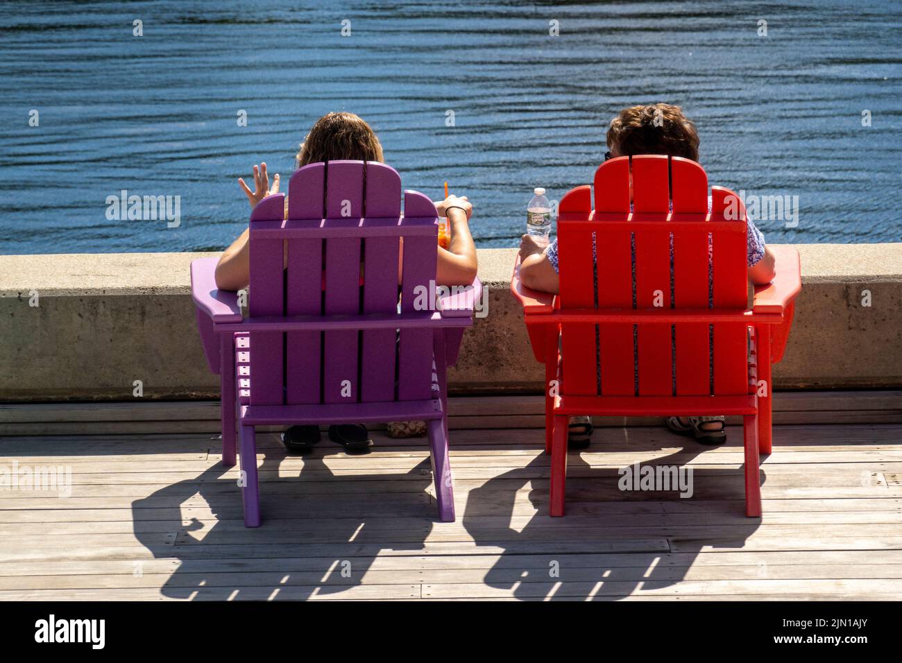 Coloridas sillas Adirondack a lo largo del Kennebec river en Hallowell Maine Foto de stock