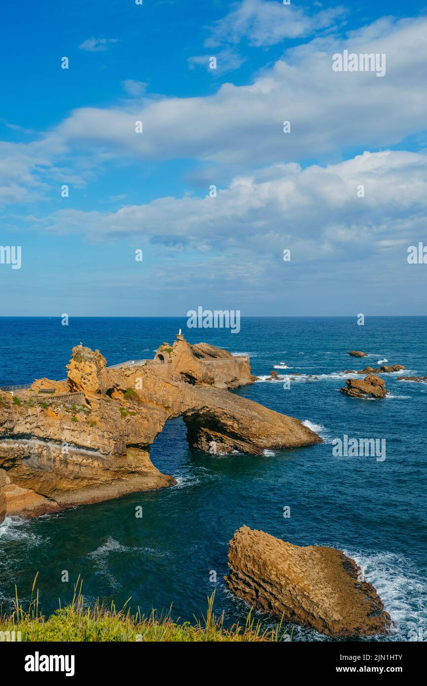 Una vista sobre el Rocher de la Vierge en Biarritz, Francia, una peculiar formación rocosa en el océano Atlántico coronado con la imagen de la Virgen María, y. Foto de stock