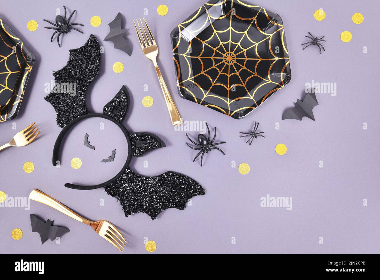 Halloween fiesta plana con placas de tela de araña, diadema de murciélago traje, arañas y confeti sobre fondo violeta Foto de stock