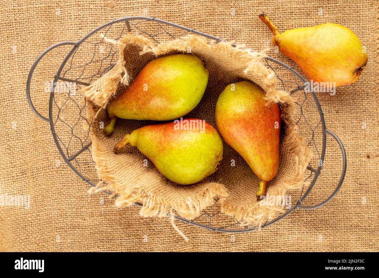 Cuatro peras maduras dulces con un núcleo en un tejido de yute, primer plano, vista superior. Foto de stock