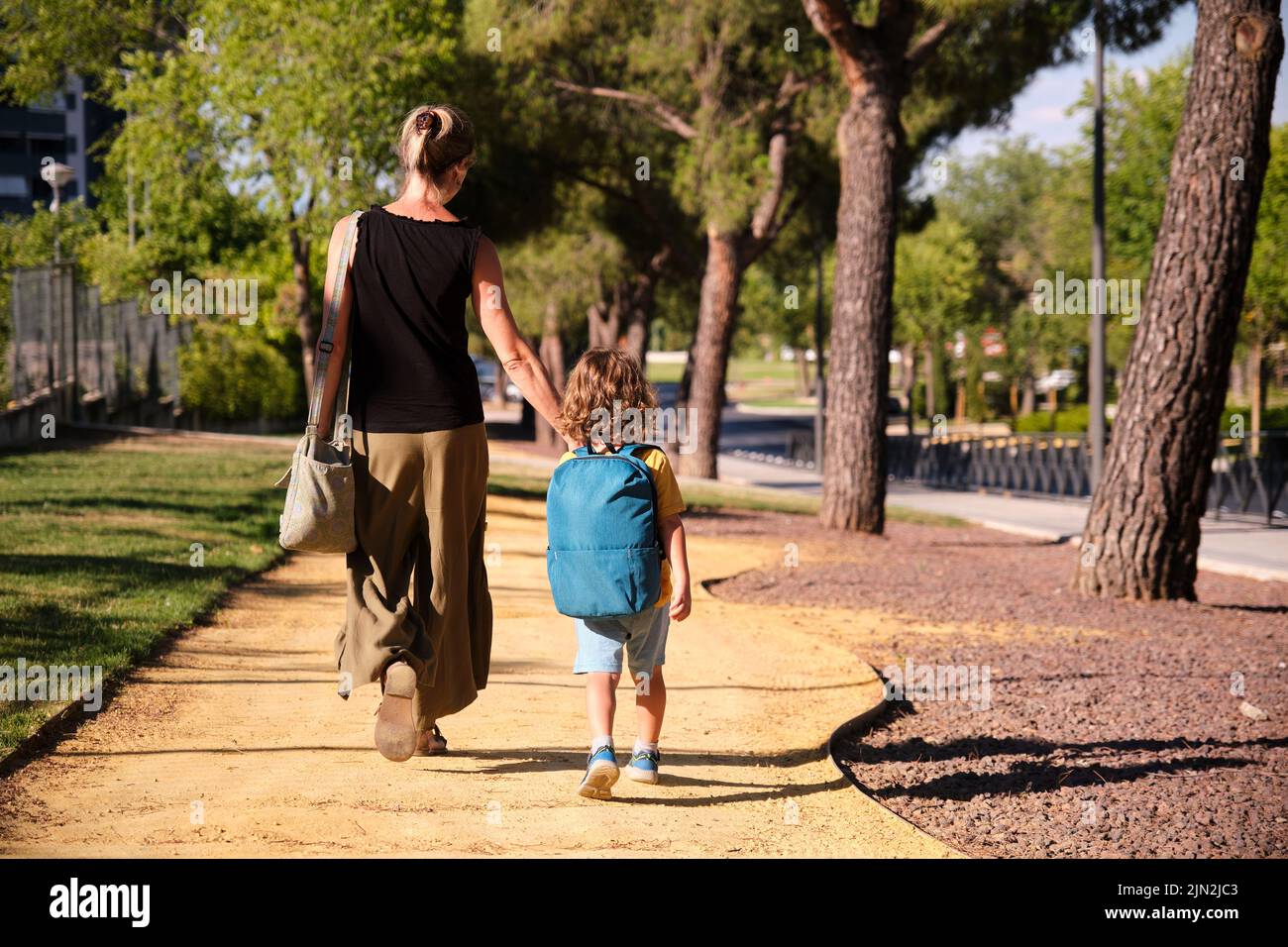 Una mujer adulta de mediana edad caminando con su hijo mientras va a la escuela Foto de stock