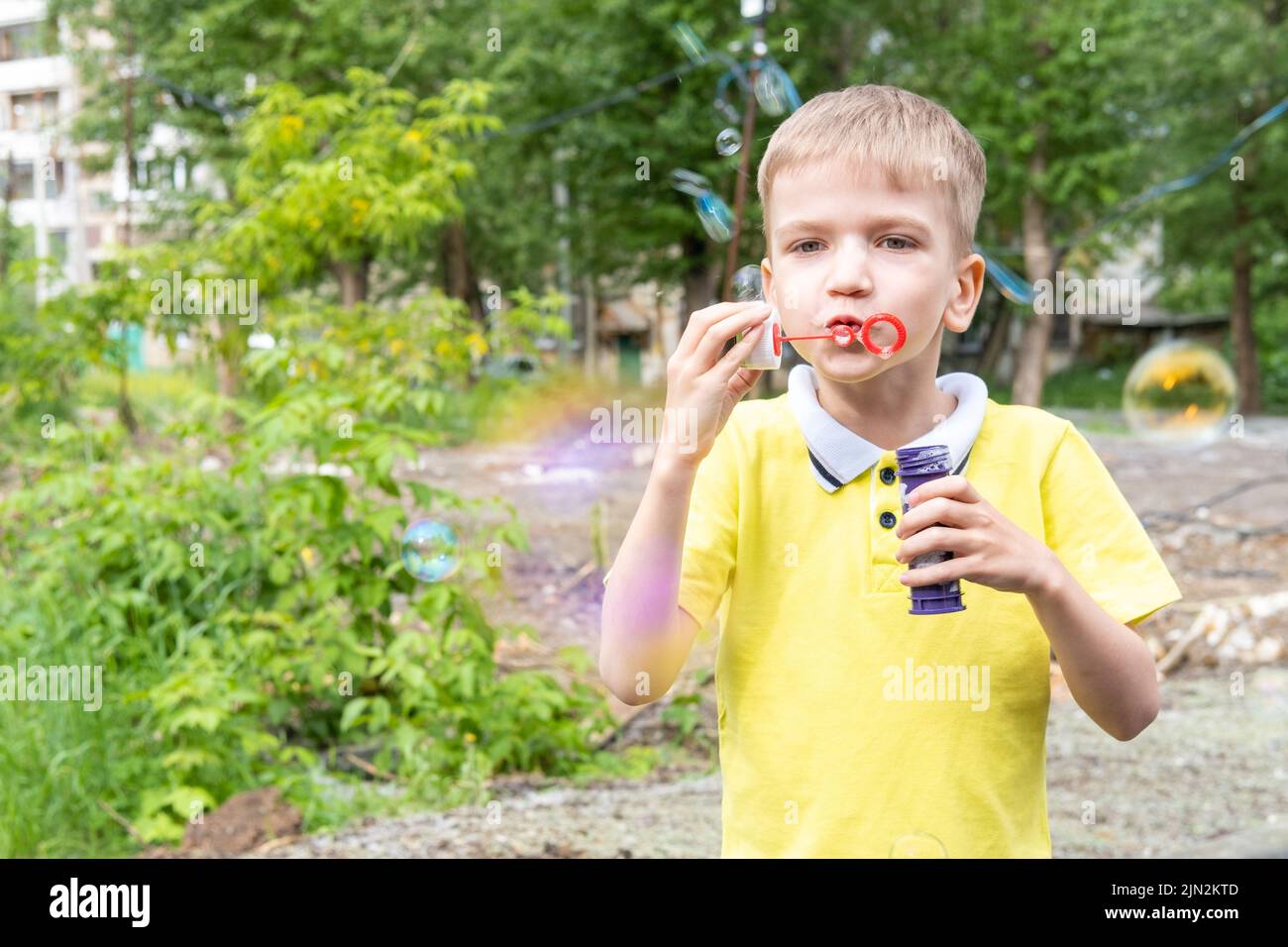 Feliz niño pequeño divertirse soplando coloridas burbujas arco iris al aire libre en el jardín, verano, jugar al aire libre, divertirse, concepto de vacaciones. Foto de stock