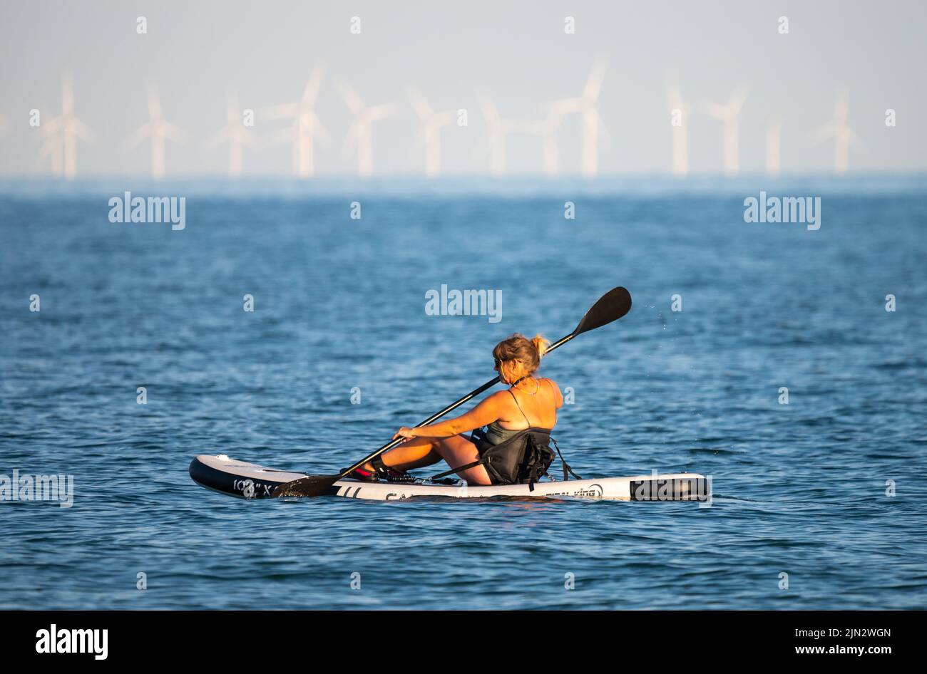 Littlehampton, West Sussex, Reino Unido. Lunes 8th de agosto de 2022. Una señora rema en el mar a última hora de la tarde mientras la ola de calor continúa en la costa sur. Crédito: Geoff Smith/Alamy Live News Foto de stock