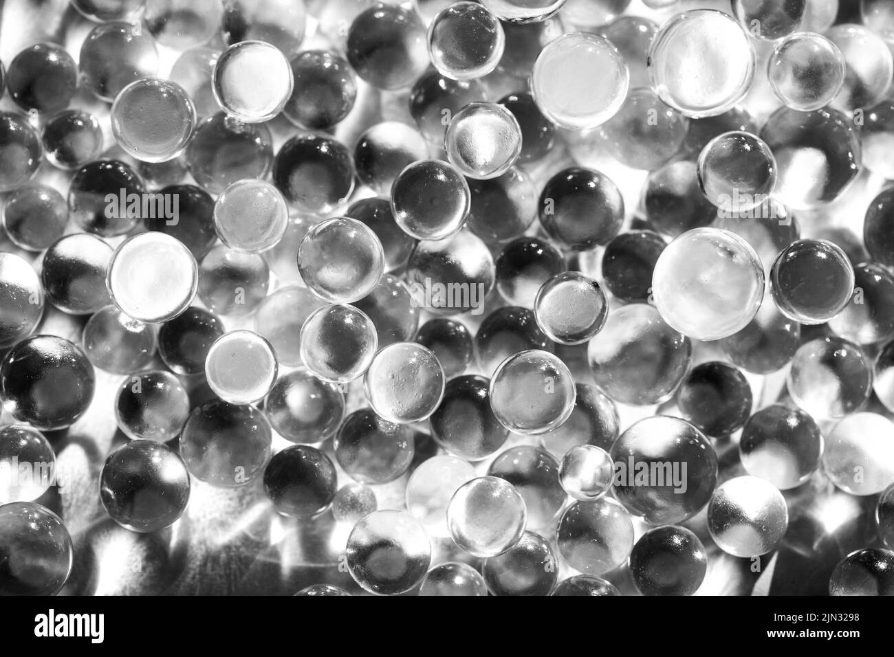 Poco bolas de vidrio en la luz solar directa, macro. Resumen Antecedentes, fotografía en blanco y negro Foto de stock