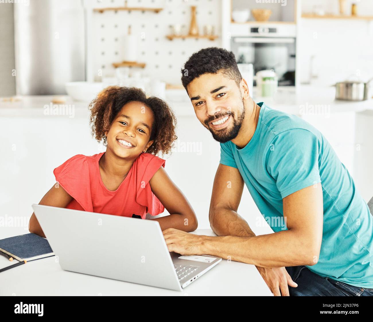 padre e hija divirtiéndose haciendo la tarea con el ordenador portátil en casa Foto de stock