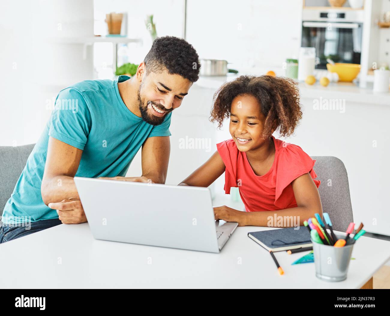 padre e hija divirtiéndose haciendo la tarea con el ordenador portátil en casa Foto de stock