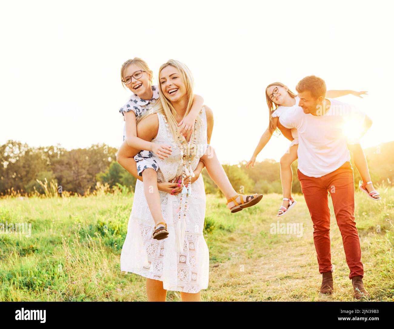 niño familia al aire libre madre mujer padre niña feliz estilo de vida felicidad divertirse bonding piggyback Foto de stock