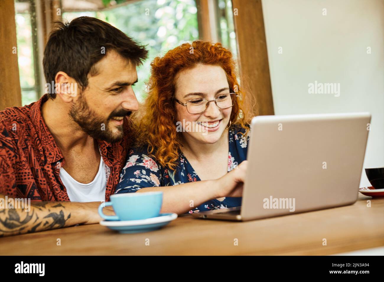 divertido mujer hombre pareja café feliz juntos sonriendo amor utilizando comunicación cafetería ordenador portátil Foto de stock