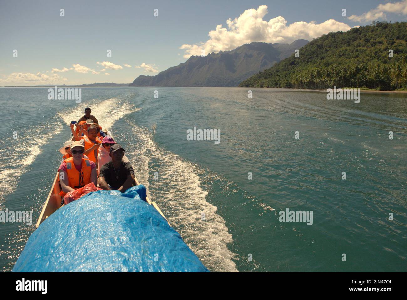 Un barco que transporta turistas navega por el agua frente a la costa de la isla de Seram, cerca de la aldea de Moral en Seram Utara Barat, Maluku Tengah, Maluku (Indonesia). Foto de stock