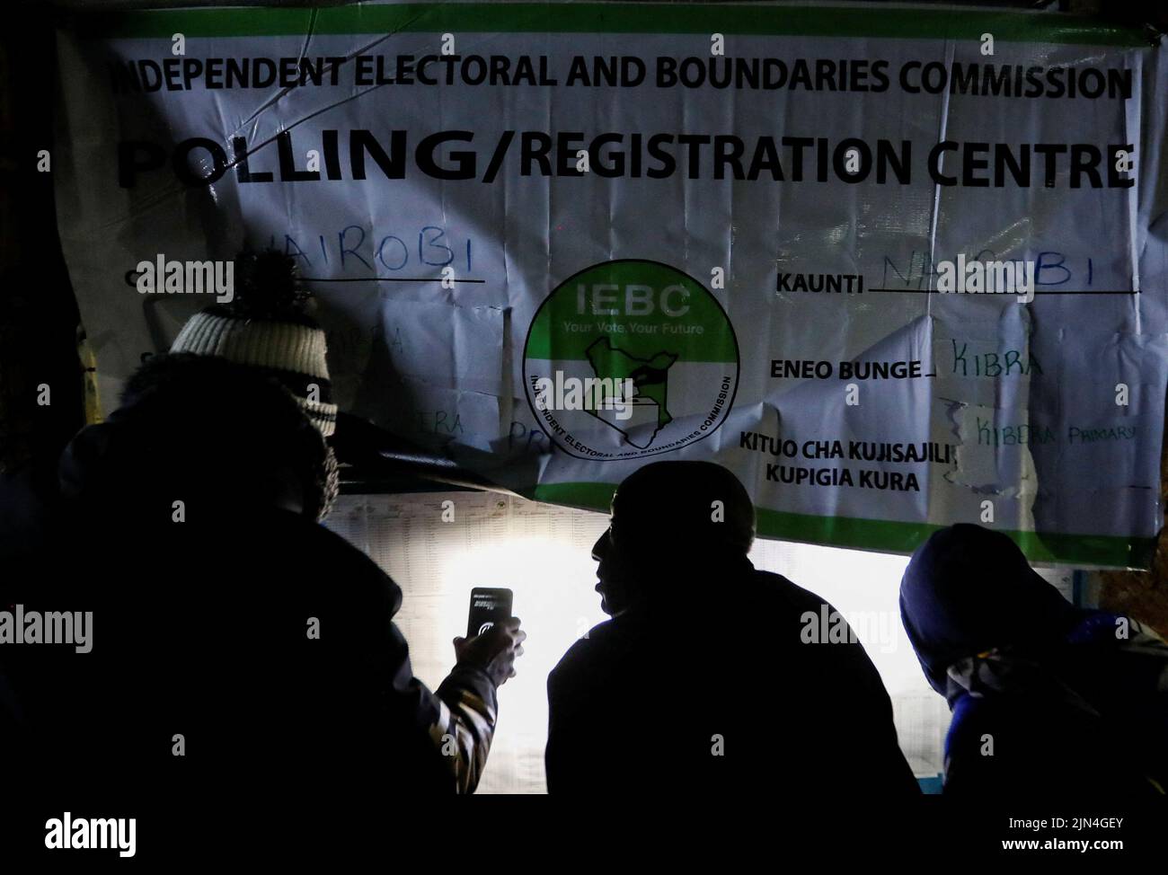 Un votante utiliza un teléfono móvil para buscar los nombres a través de una lista de votantes pegada en la pared de la Comisión Electoral Independiente y de Fronteras (IEBC) antes de la apertura de las urnas en la escuela primaria de Kibera en Nairobi, Kenia, el 9 de agosto de 2022. REUTERS/Thomas Mukoya Foto de stock