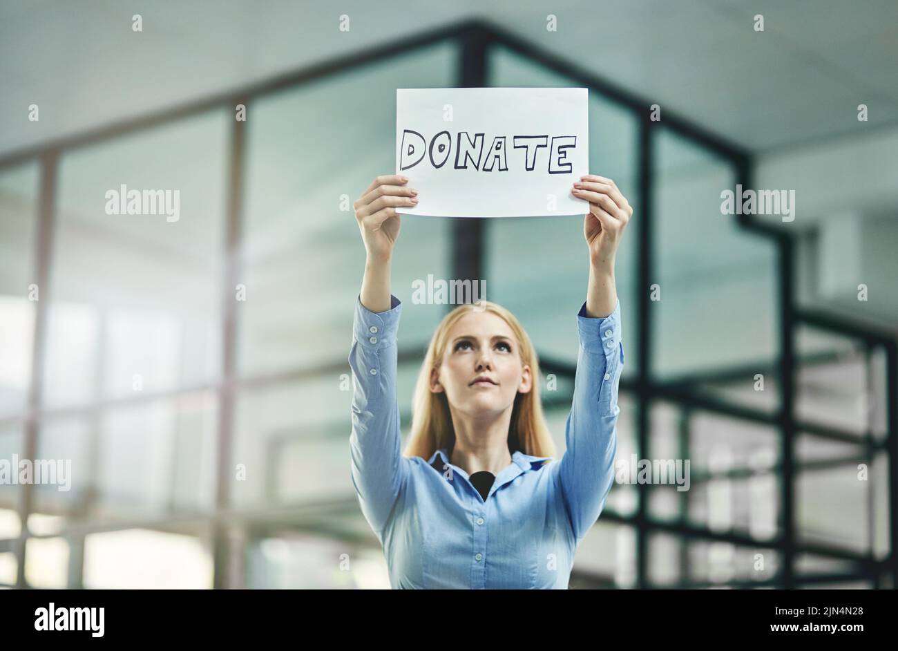 Donación, caridad y recaudación de fondos mientras se sostiene un cartel y se pide ayuda y apoyo en la oficina corporativa. Mujer de negocios y fundación benéfica Foto de stock