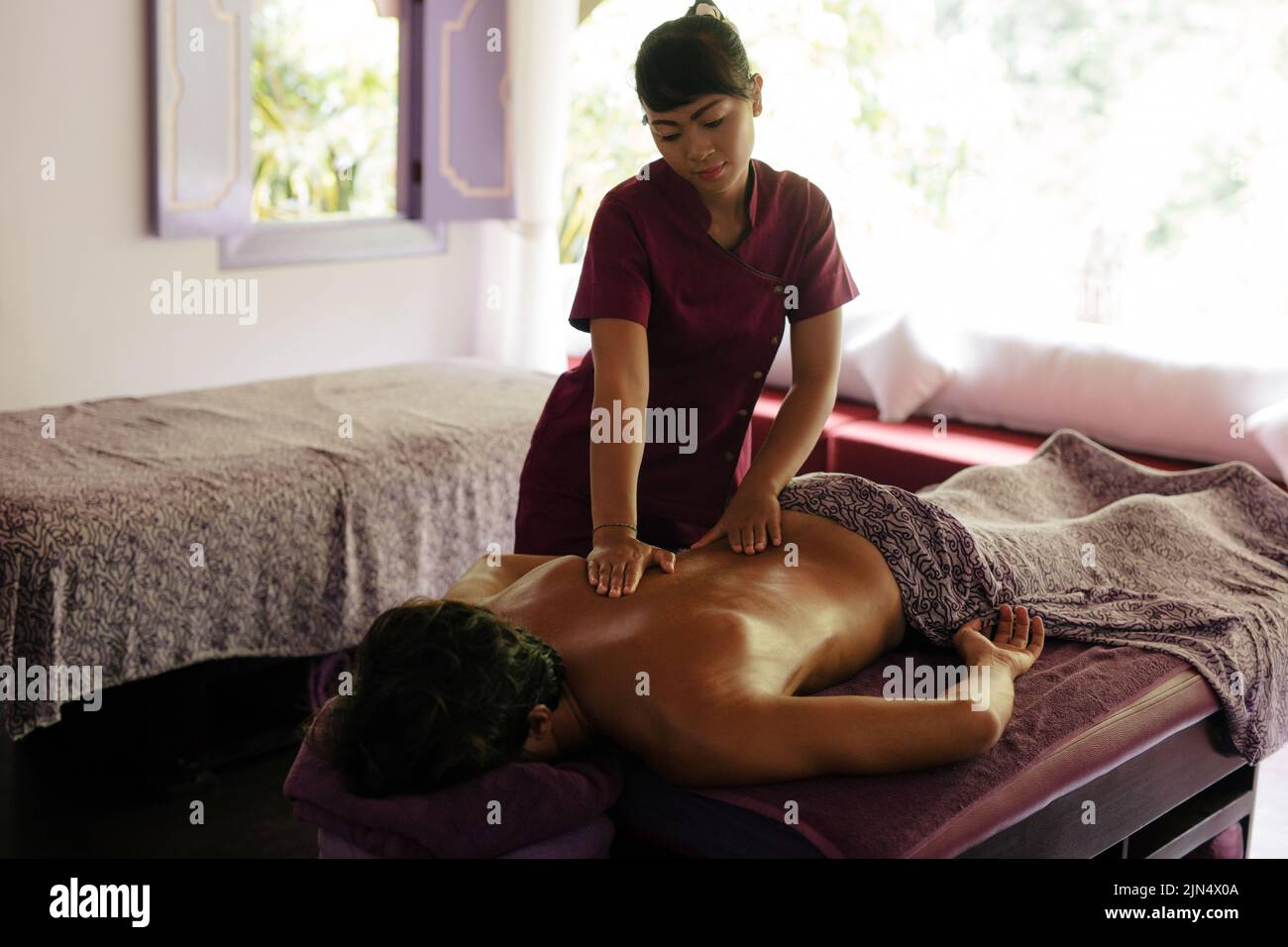 Plano de terapeuta de masaje femenino masajeando al hombre en el spa de día. Foto de stock