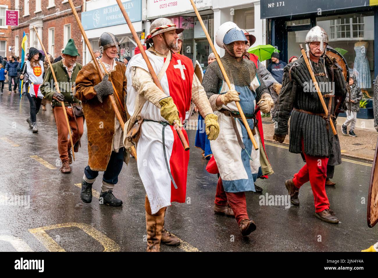 Las personas vestidas con trajes medievales participan en una procesión por las calles de Lewes durante el evento de la Batalla de Lewes para el Re-Enactment, Lewes, Reino Unido. Foto de stock