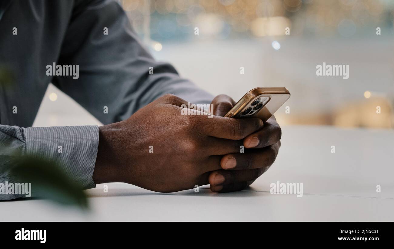 Primer plano hombre manos escribir en el teléfono móvil irreconocible hombre de negocios afroamericano comprobar el correo electrónico trabajar de forma remota con un smartphone joven Foto de stock