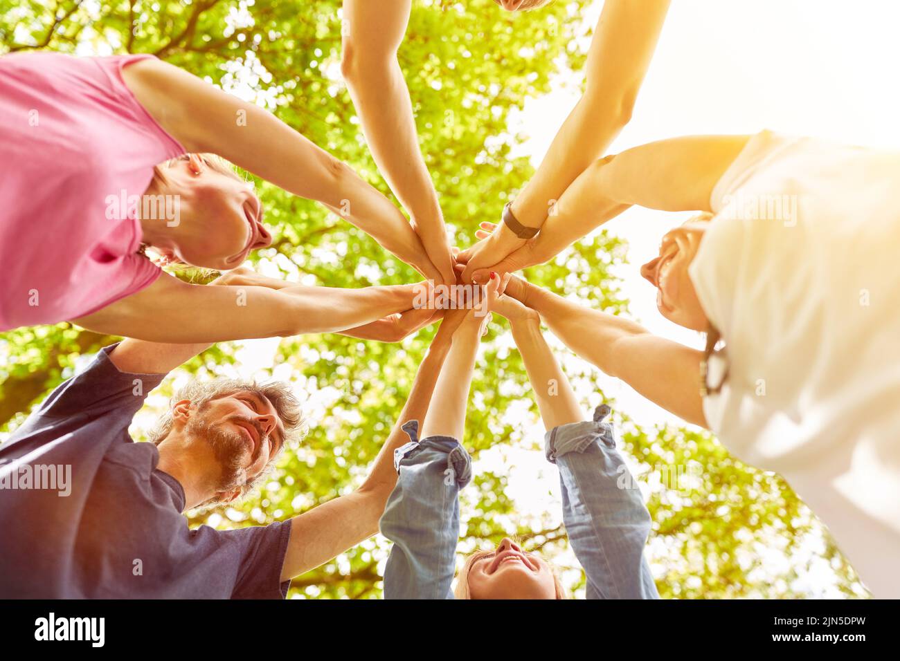 Feliz grupo de personas como un equipo estrechar las manos en un círculo para la motivación Foto de stock