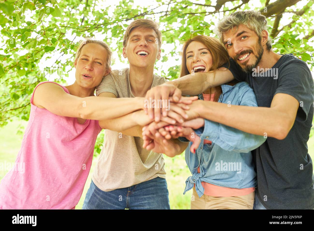 Feliz grupo de amigos apilando las manos para la comunidad y la construcción de equipos Foto de stock