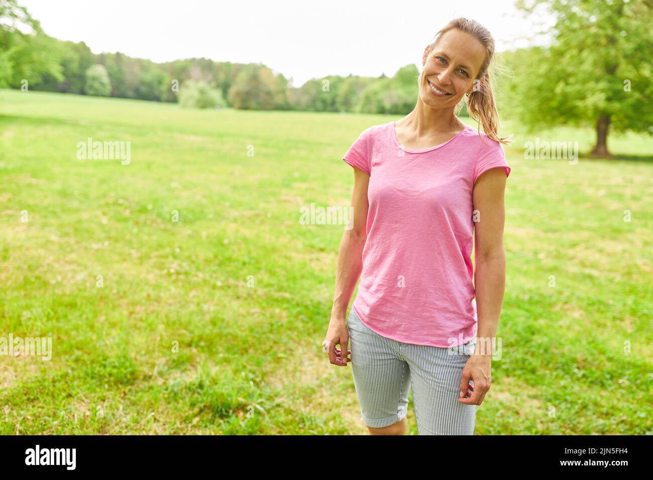 Mujer joven deportiva en vestido deportivo en un prado en verano Foto de stock