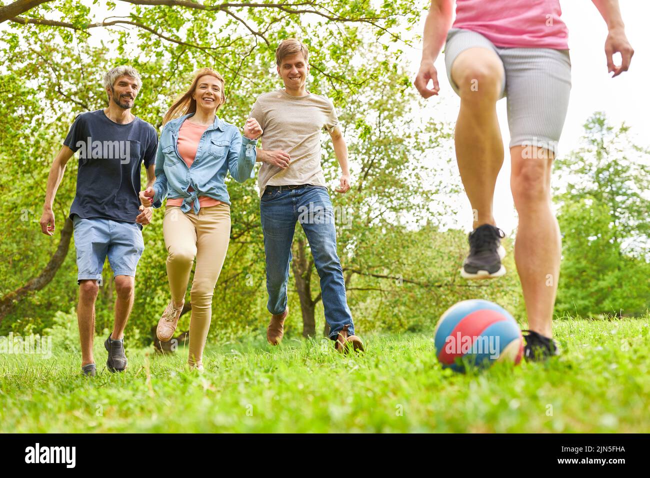 Los jóvenes se divierten jugando fútbol en un prado en verano en el evento de equipo Foto de stock