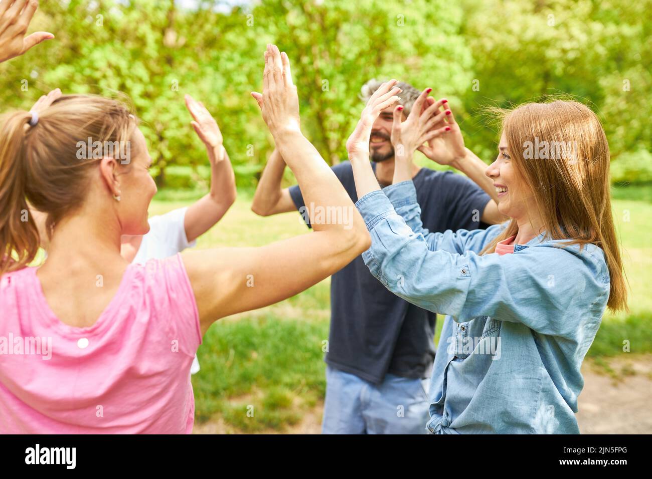 Grupo de jóvenes se divierten dando alto cinco para la motivación en el taller al aire libre Foto de stock