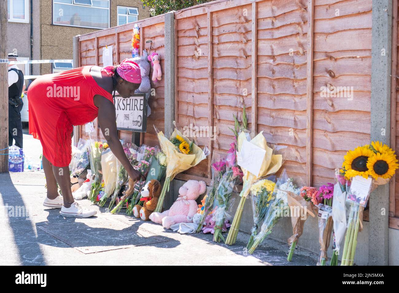 Una mujer pone flores cerca de Galpin's Road en Thornton Heath, al sur de Londres. El Servicio de Ambulancias de Londres ha confirmado la muerte de un niño y tres personas están en el hospital después de que la terraza se derrumbara tras una explosión y un incendio el lunes. Fecha de la foto: Martes 9 de agosto de 2022. Foto de stock