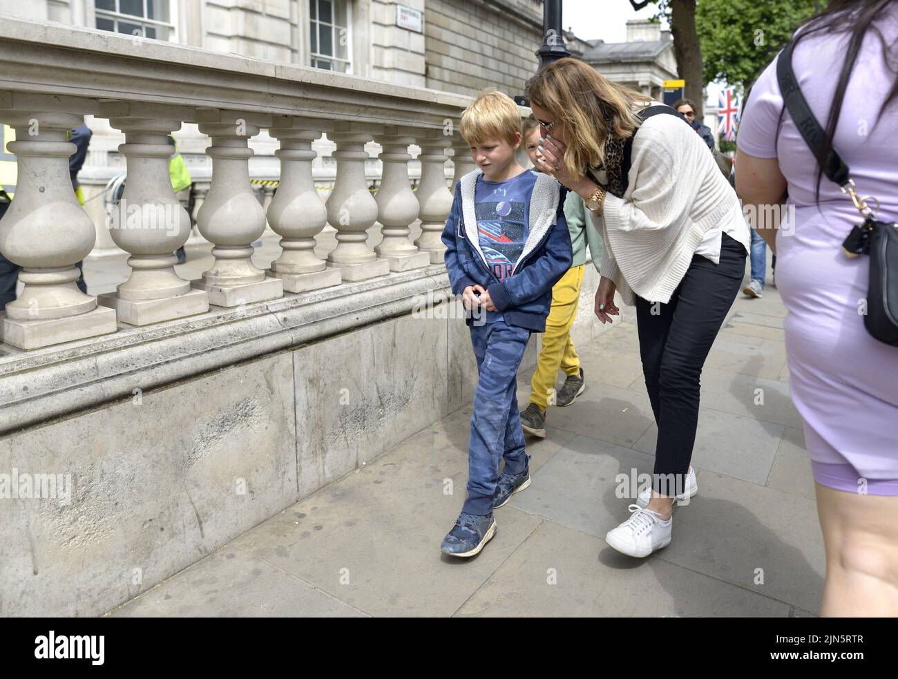 Londres, Inglaterra, Reino Unido. Madre susurrando a su hijo en Whitehall, Westminster Foto de stock