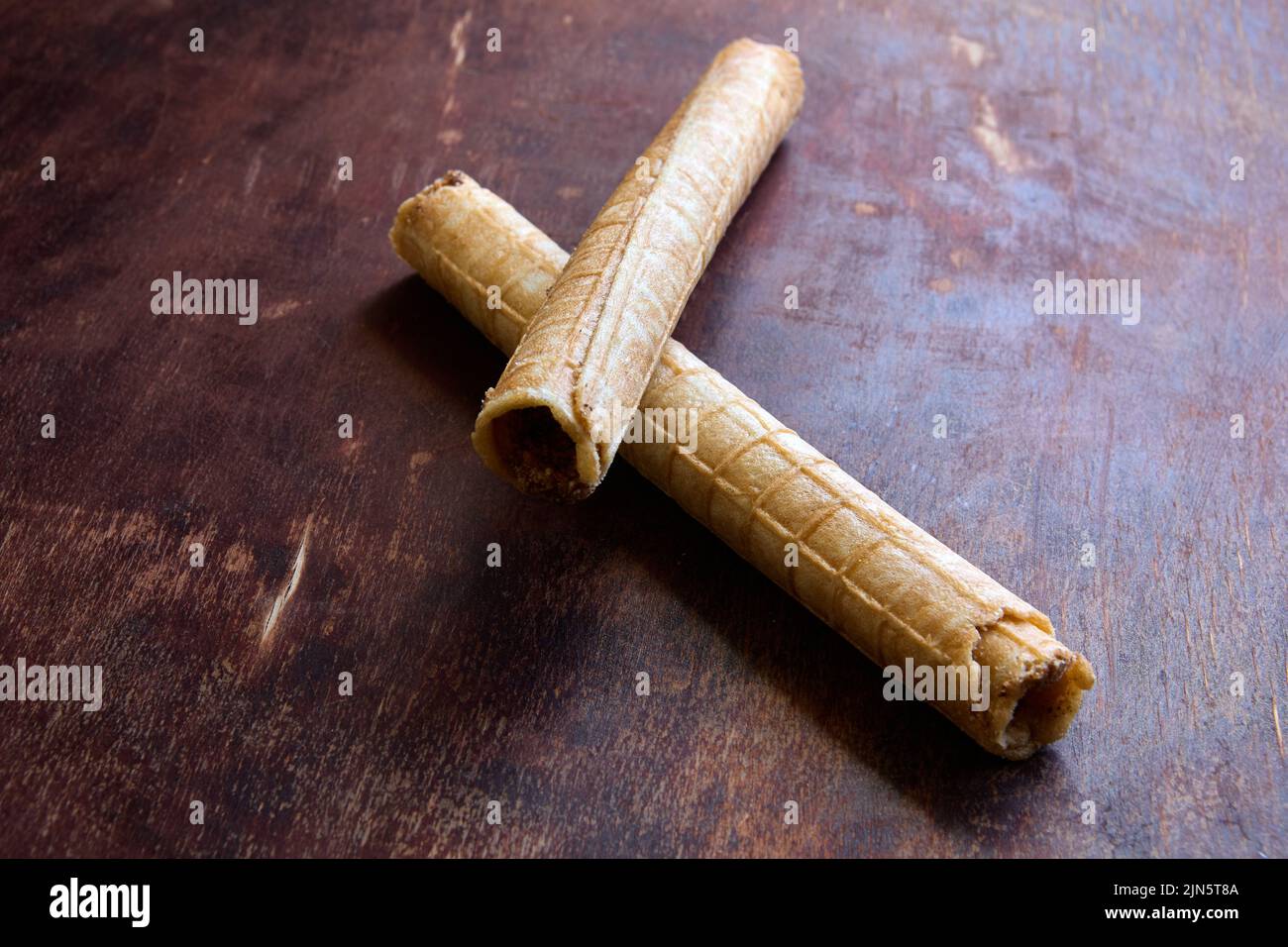 Los rollos de obleas rellenos de crema se encuentran encima de la mesa de madera de la cocina. Foto de stock