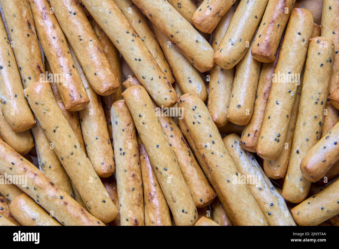 Palitos de pan crujientes con textura de semillas de amapola como telón de fondo. Foto de stock