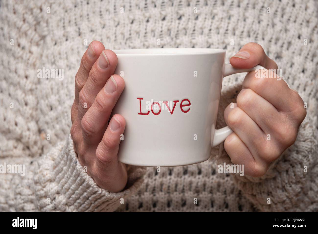 mujer sosteniendo una taza con 'amor' en ella. Foto de stock
