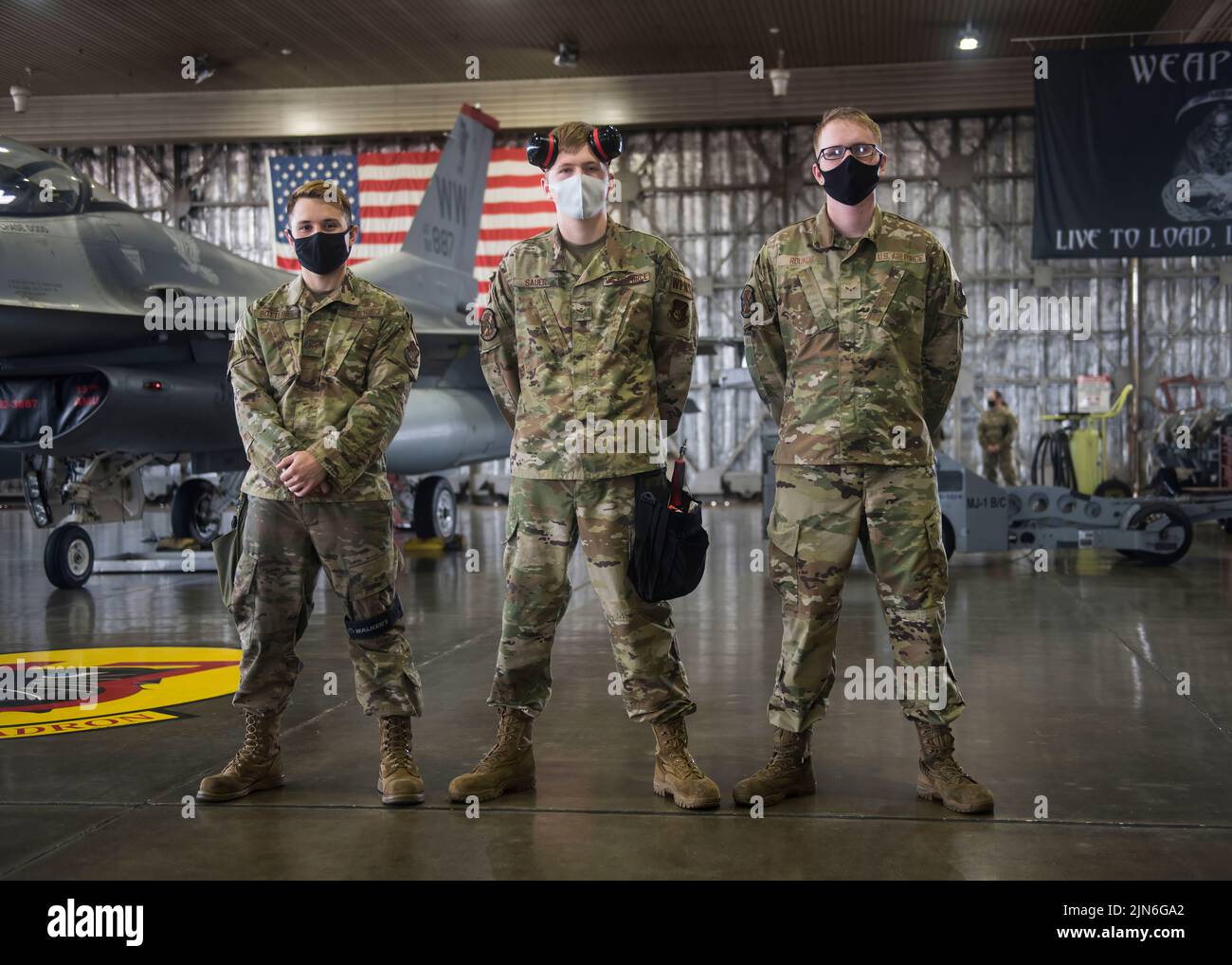 Personal de la Fuerza Aérea de EE.UU. Sgt. David Botterill (izquierda), un jefe del equipo de carga de armas, Airmen 1st Class Braedon Sauer (centro) y Cole Rounds (derecha), miembros del equipo de carga de armas, de la Unidad de Mantenimiento de Aeronaves 13th, están frente a un halcón de combate F-16 durante la competencia de carga del segundo cuarto en la Base Aérea de Misawa, Japón, el 16 de julio de 2021. Se necesitan tres miembros para preparar la aeronave, hacer una lista de verificación de las órdenes técnicas y colocar las armas en la aeronave durante la competición de carga de la manera más eficiente posible. (EE. UU Foto de la Fuerza Aérea por Airman 1st Clase Leon Redfern) Foto de stock