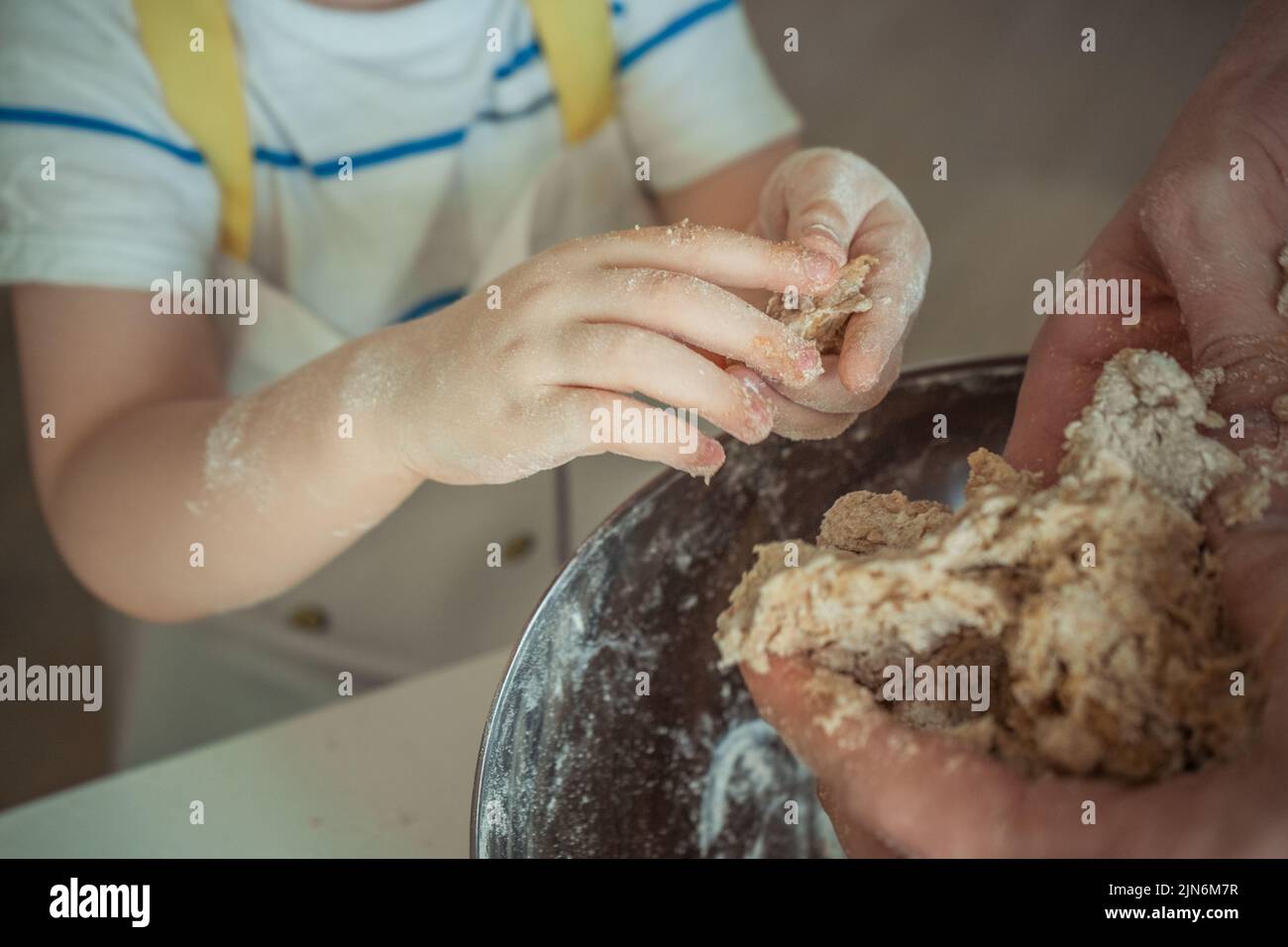 Las manos de un niño recortado están haciendo una masa para un pastel Foto de stock