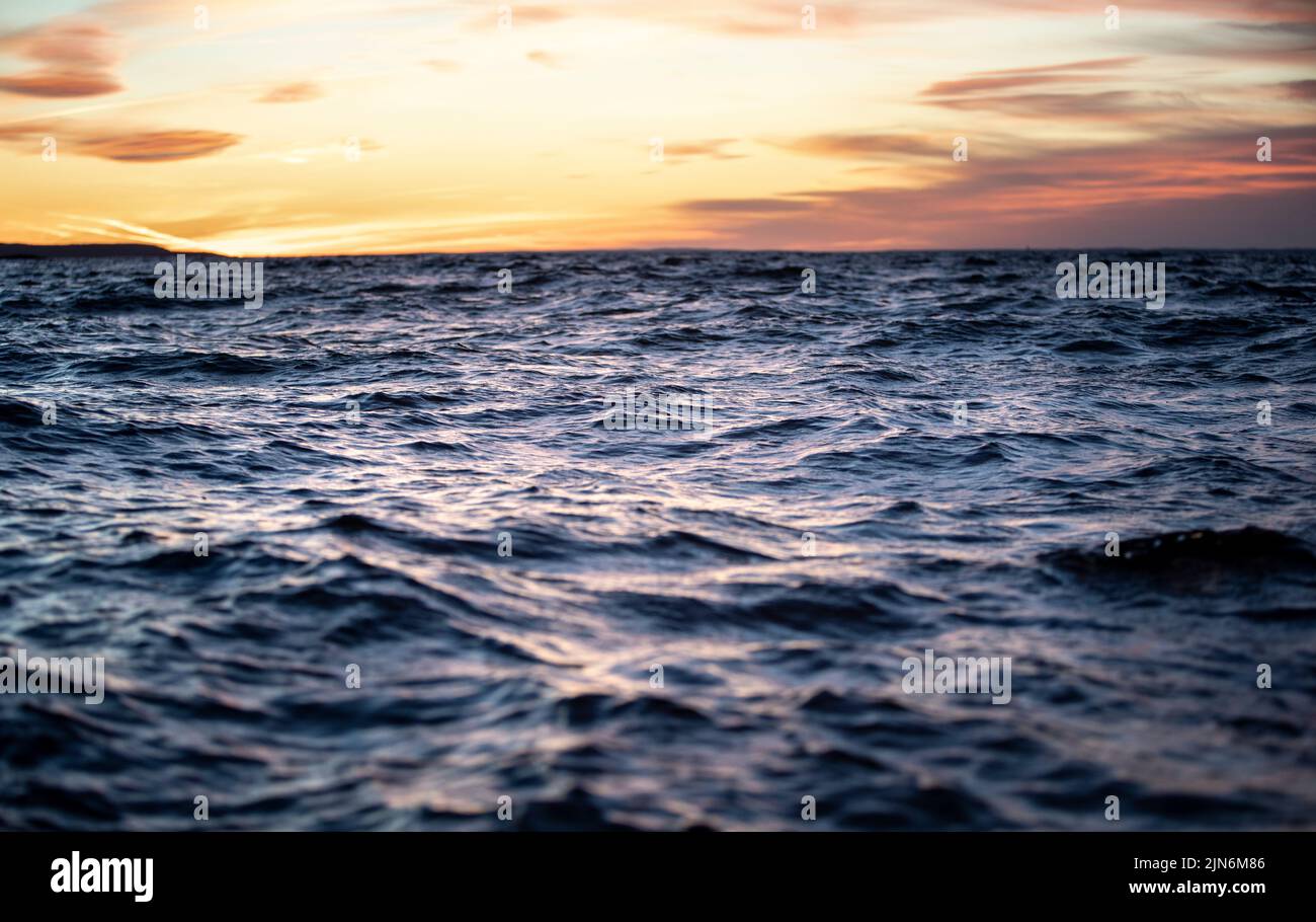 Una vista de un océano entrecortado al atardecer. Foto de stock