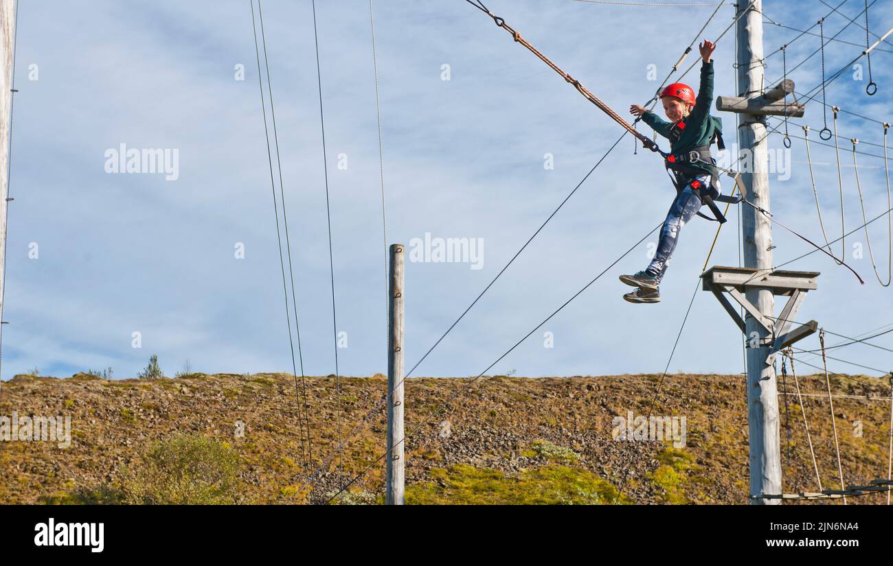 Chica utilizando un columpio gigante en el curso de alta cuerda acceso en Islandia Foto de stock