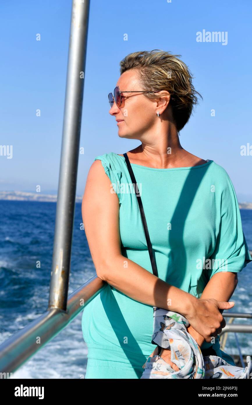 mujer de mediana edad con buena apariencia en el tablero mirando al mar Foto de stock